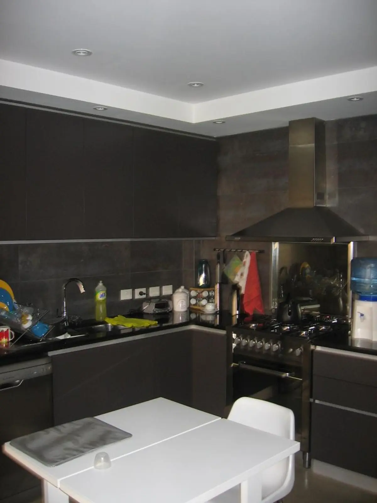 Cocina moderna negra con mesada blanca y campana de acero inoxidable — proyecto San Isidro, por Rioja Arquitectura, en San Isidro