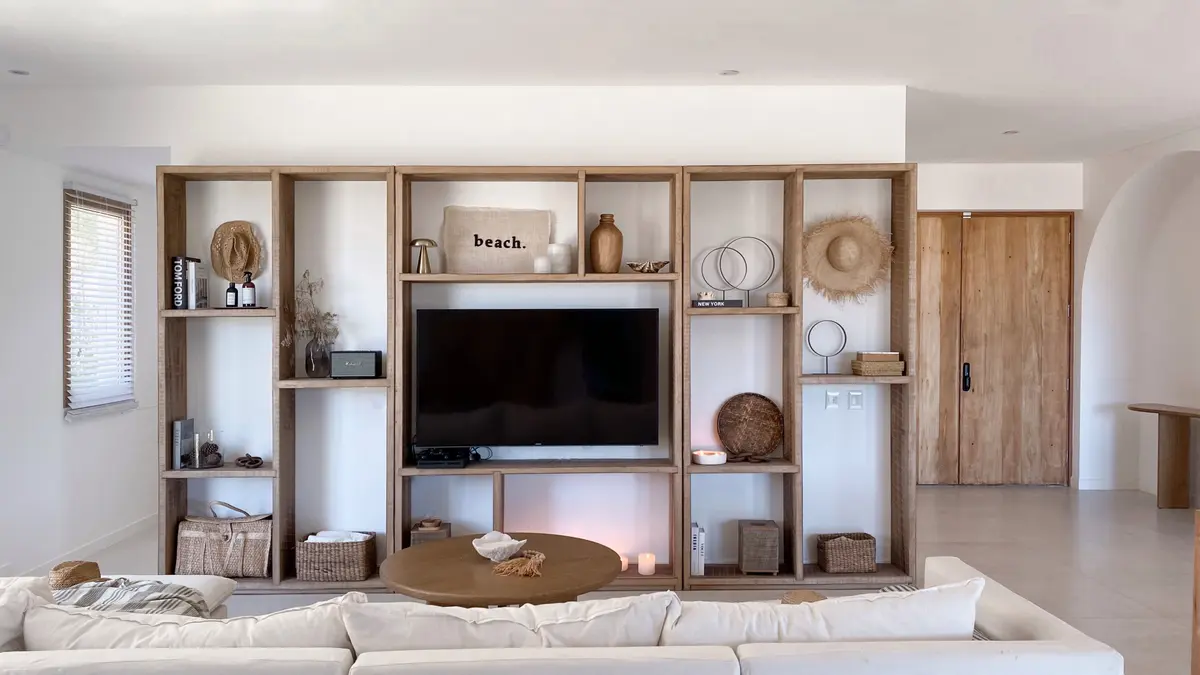 Sala de estar boho escandinava con estanterías de madera integradas — proyecto El Refugio, por Grupo Pauta Arquitectura, en Pinamar