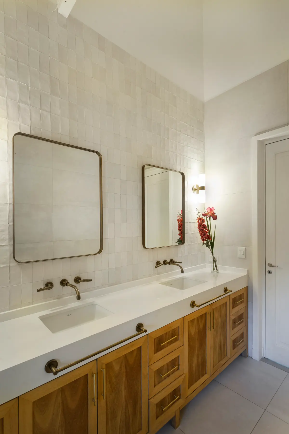 Baño moderno con doble bacha, mesada blanca, azulejos texturados y muebles de madera — proyecto Highland, por Lala Loviscek arquitecta, en Pilar