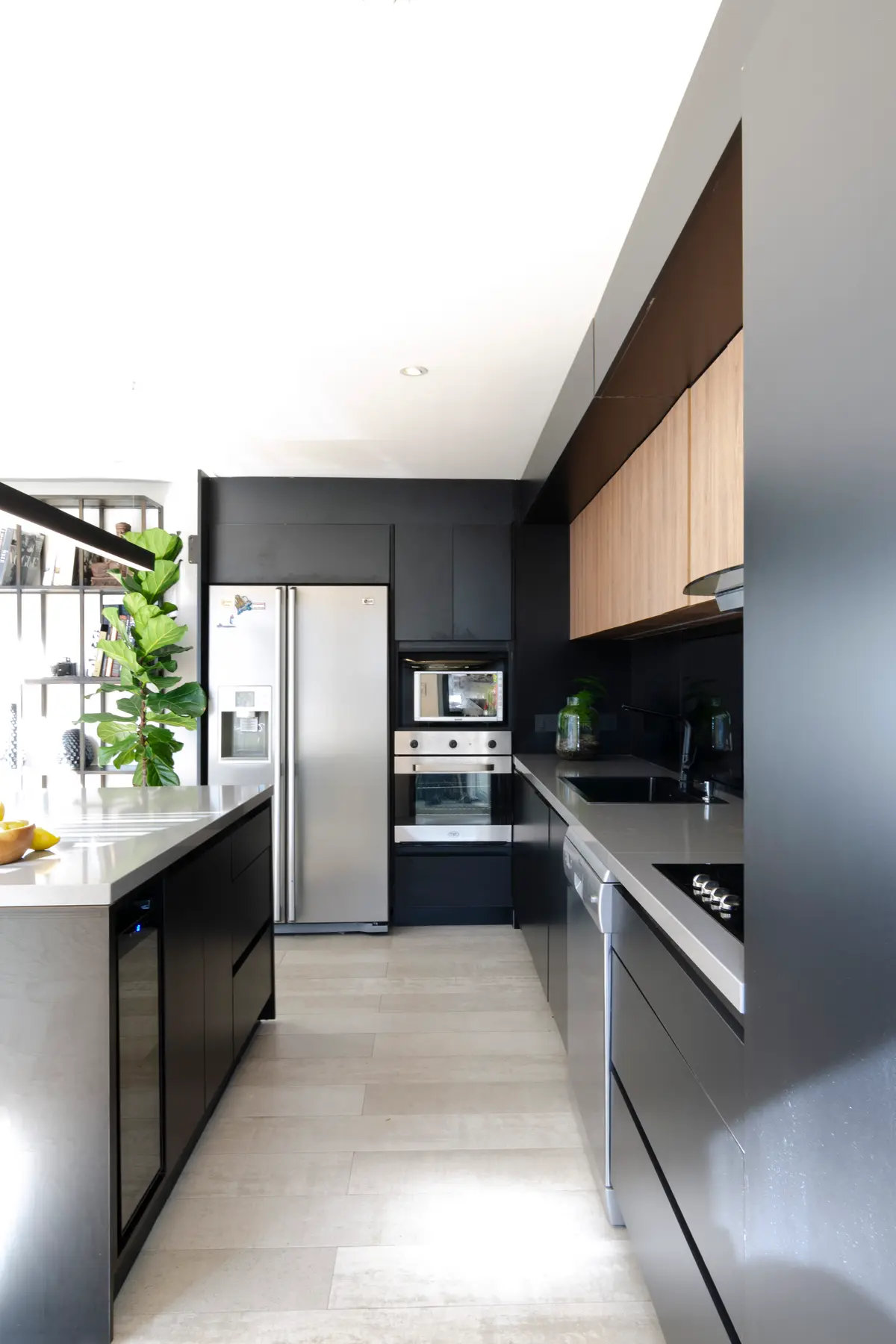 Cocina moderna con isla de madera oscura y gabinetes contrastantes — proyecto Guayra - Andrea Gonzales, por ABEJA CONCEPT, en Belgrano