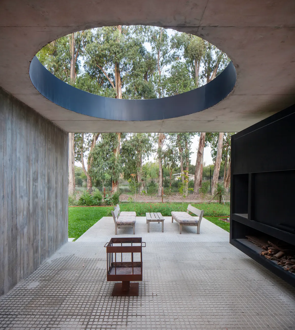 Pátio moderno com céu circular aberto para floresta e detalhes em concreto — projeto Casa SRZ, por V2 Arquitectos, em City Bell