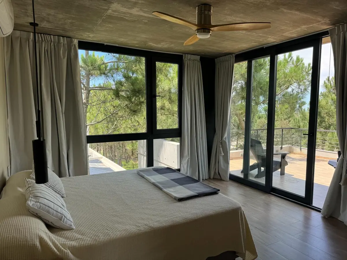 Quarto moderno com vista para floresta e teto de concreto — projeto Casa CE, por Estudio FORSCH, em Pinamar