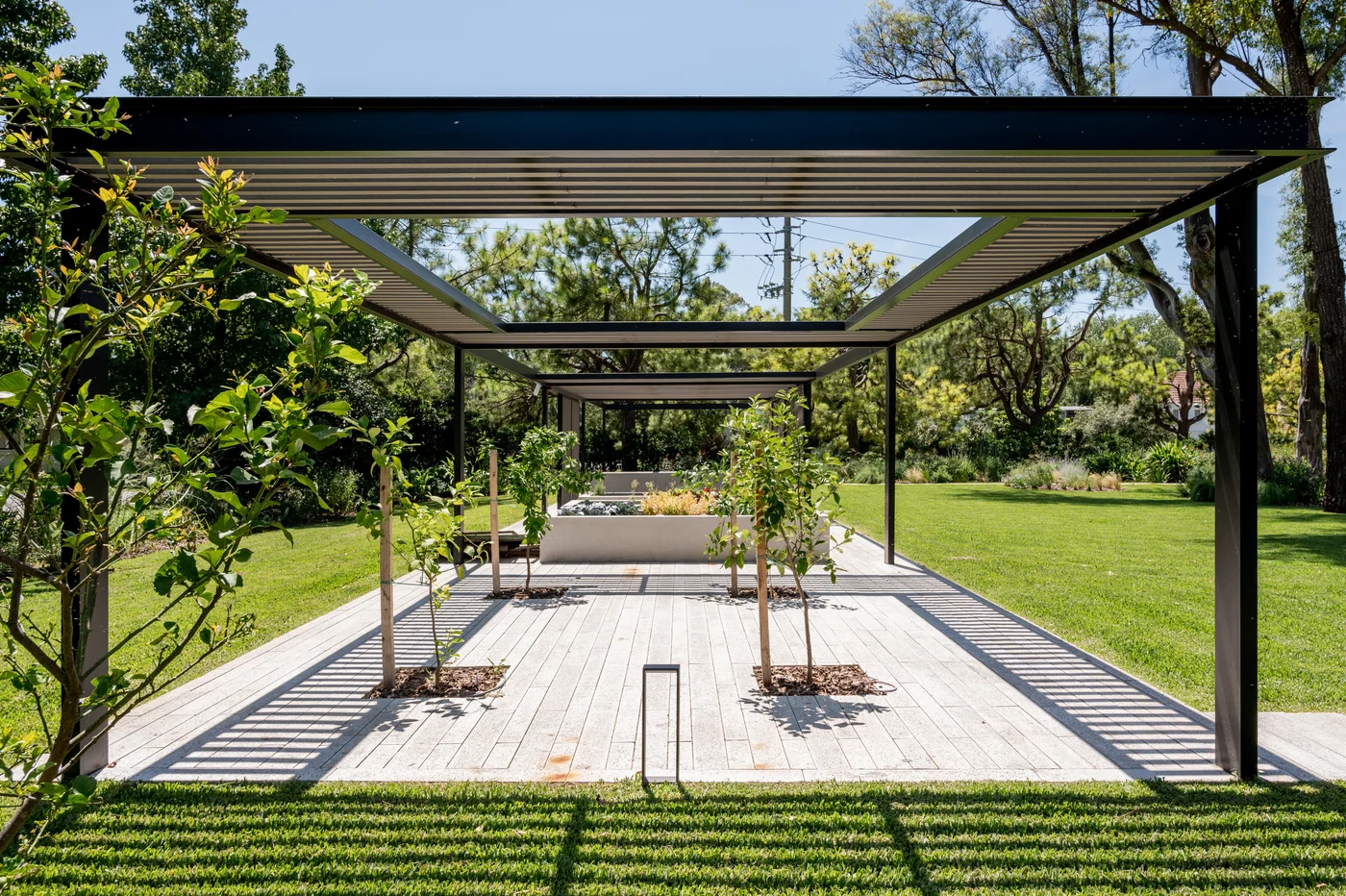 Pérgola moderna con deck de madera y césped