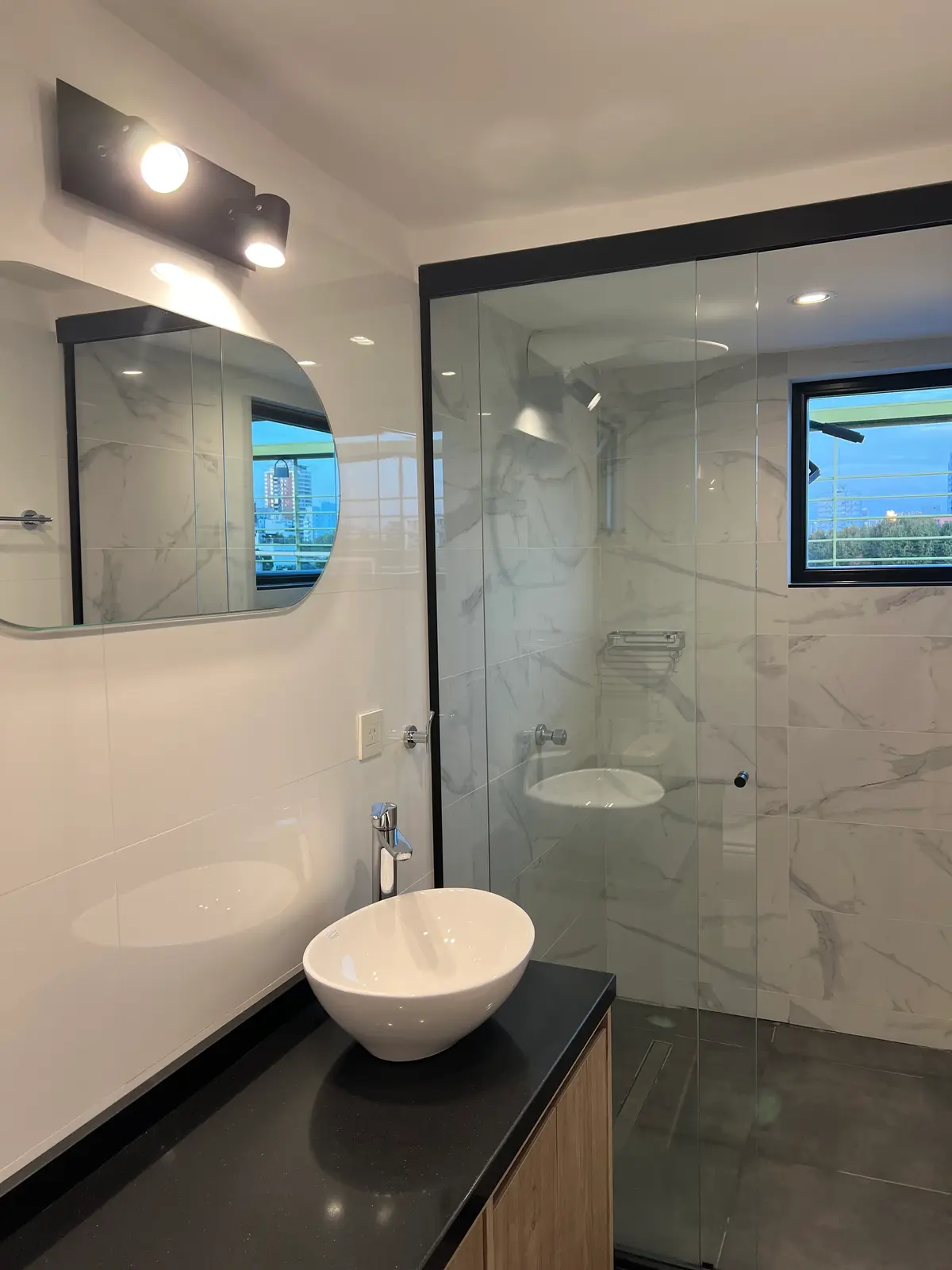 Baño moderno con ducha de mármol, lavabo sobre encimera y mueble de madera — proyecto CASITA NUÑEZ, por Estudio Grupo 32, en Núñez