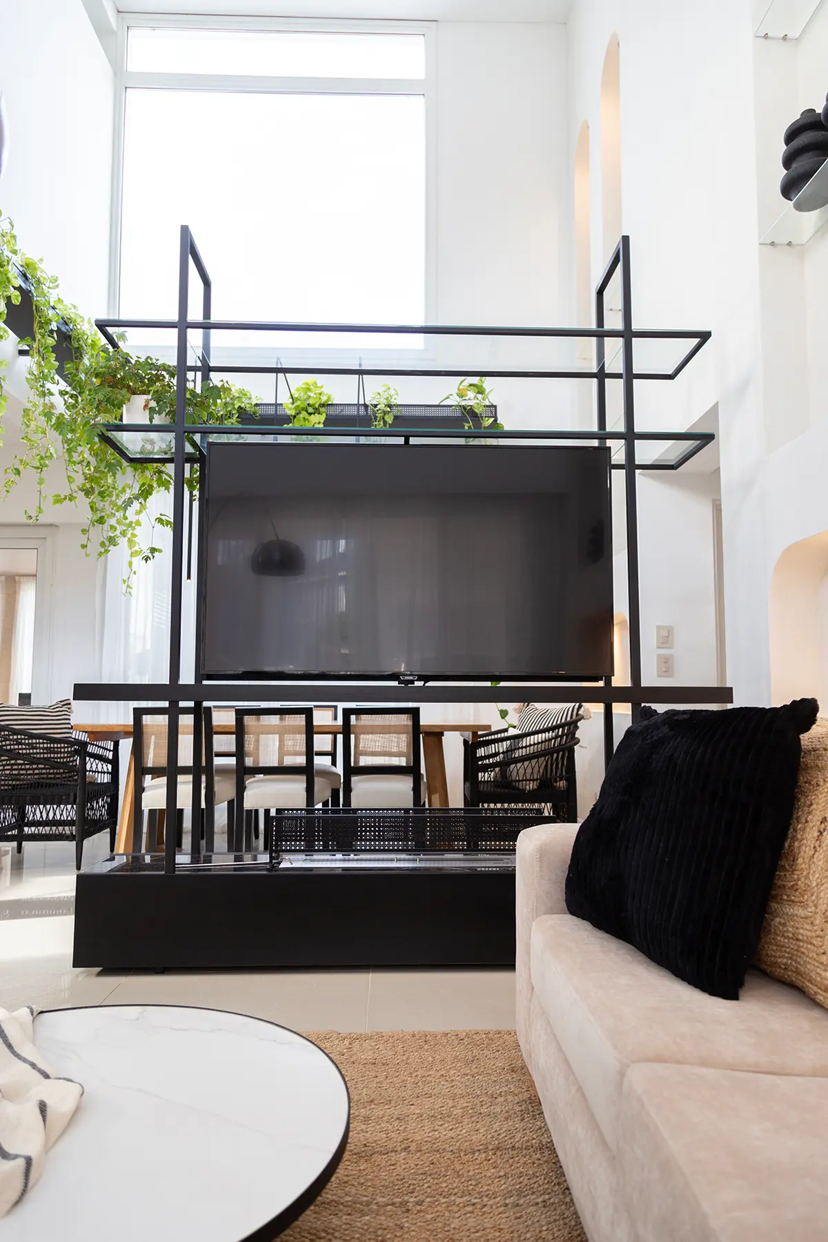 Sala moderna con estantería negra, plantas y gran ventanal — proyecto Proyecto Gaby P. , por LINEA NETA diseño interior , en Canning