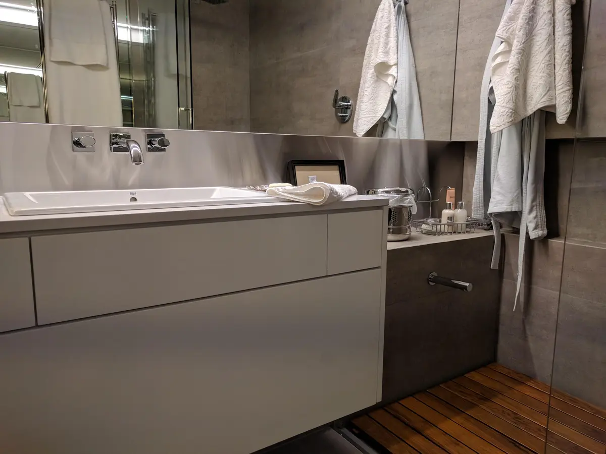 baño moderno con vanitory flotante y revestimiento de piedra — proyecto AT - Departamento en Palermo, por MLS Estudio, en Palermo