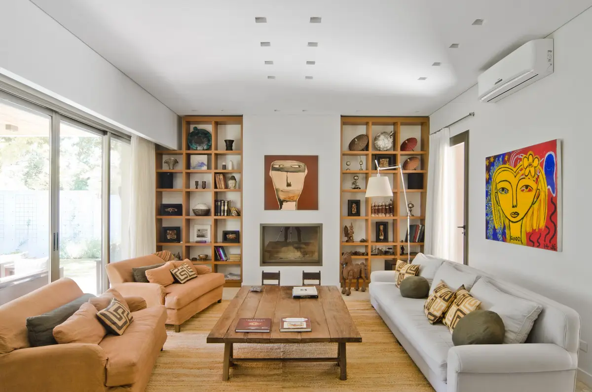 Sala de estar moderna com lareira, prateleiras de madeira e sofás curvos — projeto Casa P, por Estudio Dado, em San Isidro