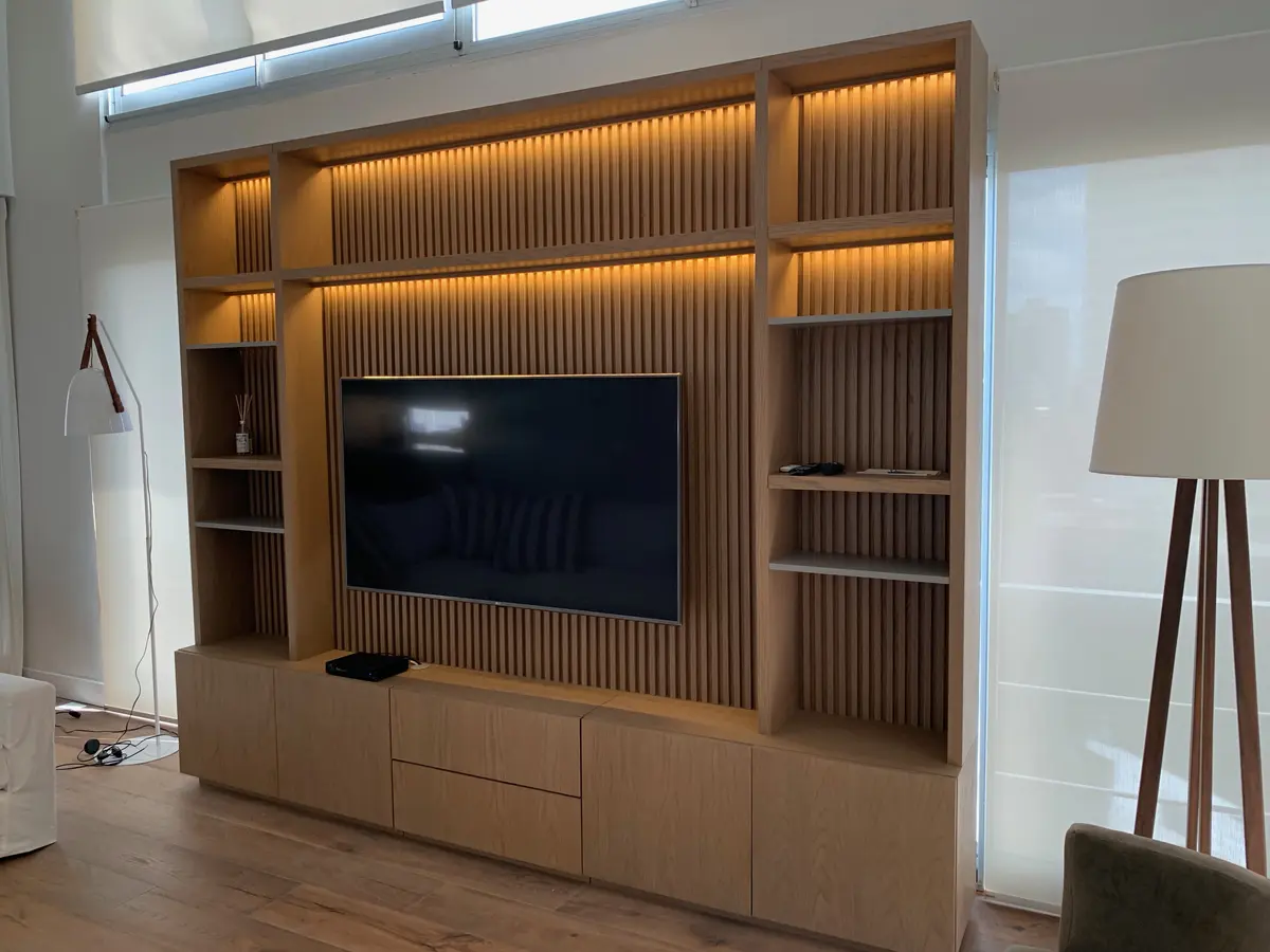 Sala de estar moderna con pared de lamas de madera e iluminación LED — proyecto Piso en Nuñez, por Gutman+Lehrer Arquitectas, en Núñez