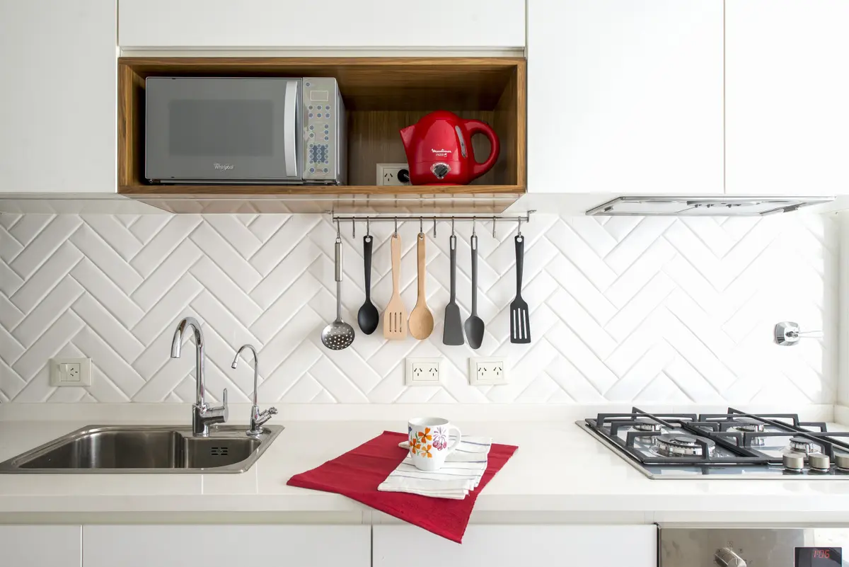 Cocina moderna con azulejos blancos tipo espiga y estante flotante de madera — proyecto Oro, por Estudio Arq. María Sioli, en CABA