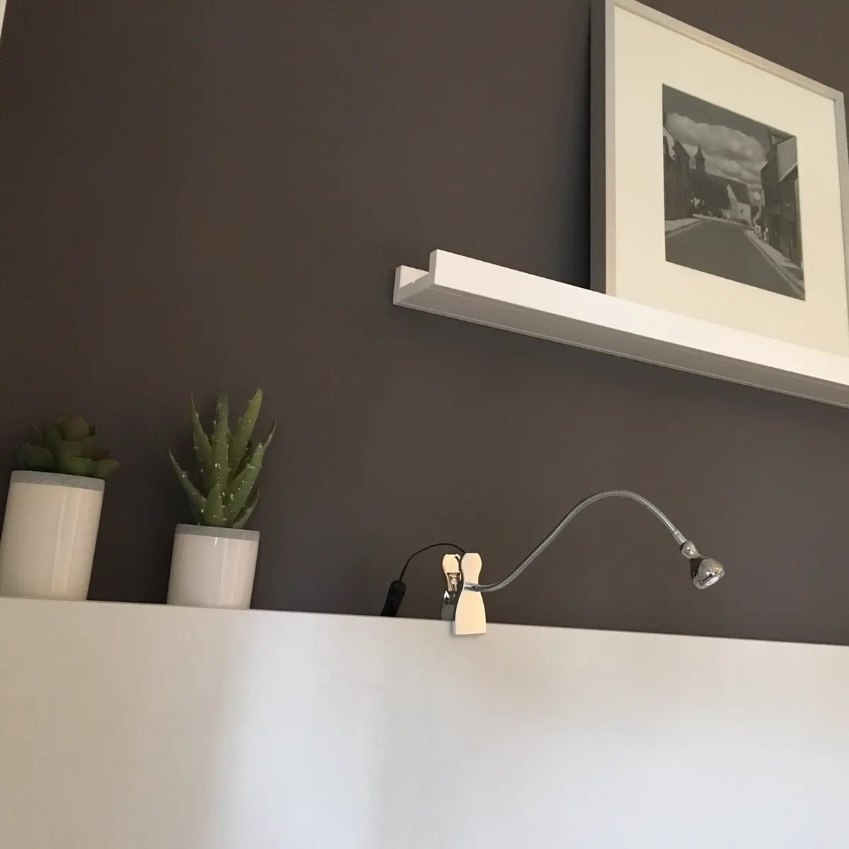 Dormitorio moderno con estante blanco, arte y plantas sobre pared gris — proyecto Ortega y Gasset, por Mgc.arq, en CABA