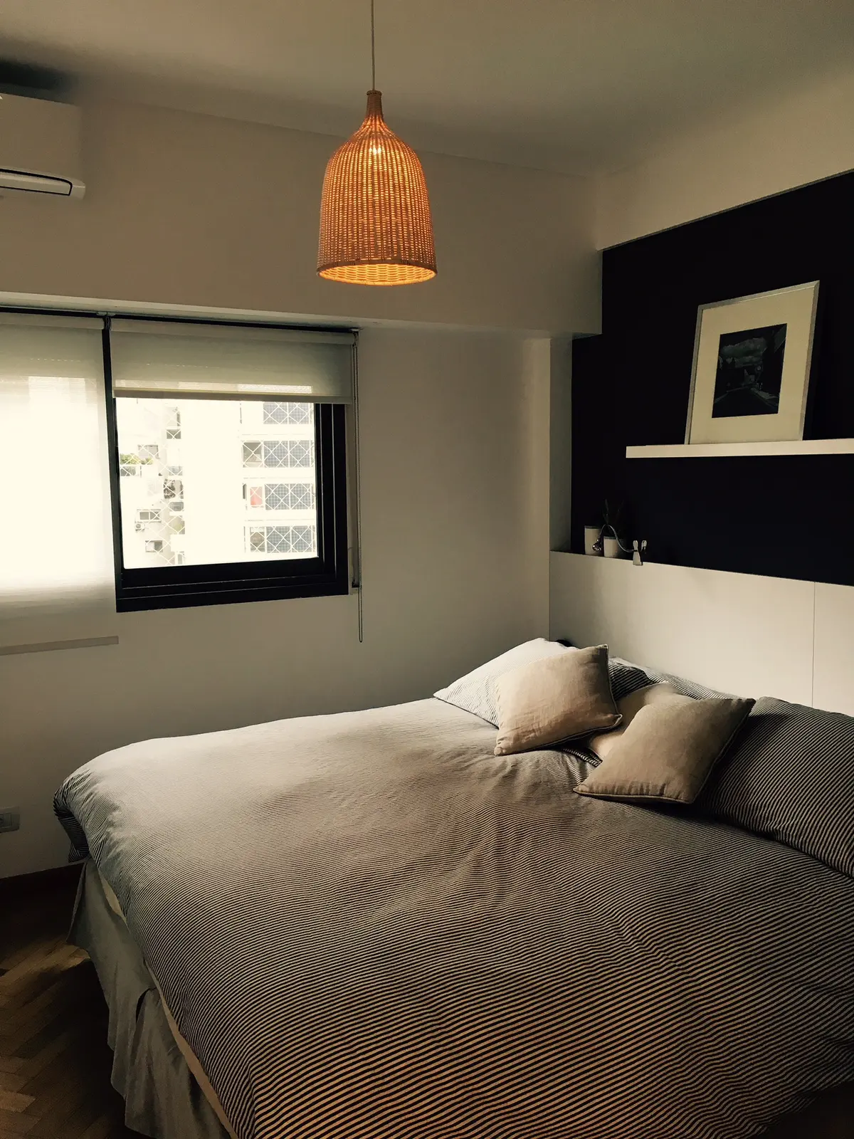 dormitorio moderno con cama de rayas, lámpara colgante de ratán y pared negra — proyecto Ortega y Gasset, por Mgc.arq, en CABA