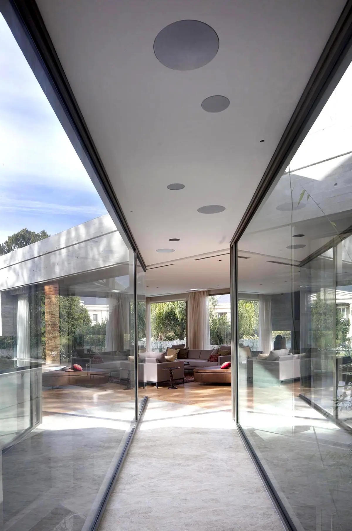 Sala de estar moderna com corredor de vidro e muita luz natural — projeto Acasusso, por Remy Arquitectos, em Acassuso