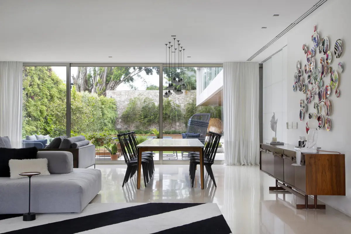 Living moderno con ventanal integrado al jardín y comedor elegante — proyecto BM House, por Studio Ro-ca