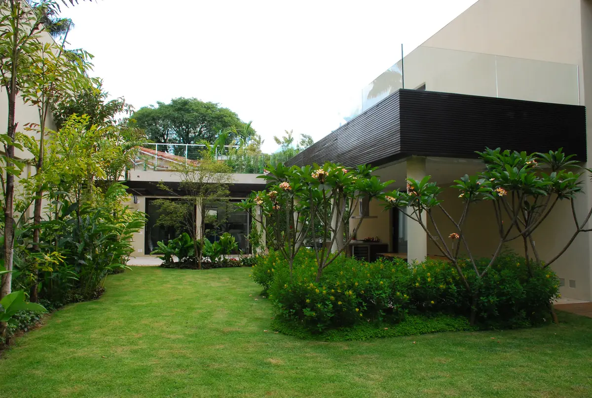 Patio con césped, árboles y pérgola de madera junto a casa moderna — proyecto Residência EC, por Gil Fialho
