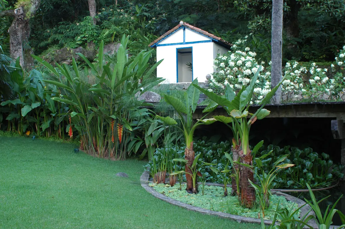 Casilla azul y blanca en jardin con casuarinas y flores blancas — proyecto Residência RC, por Gil Fialho