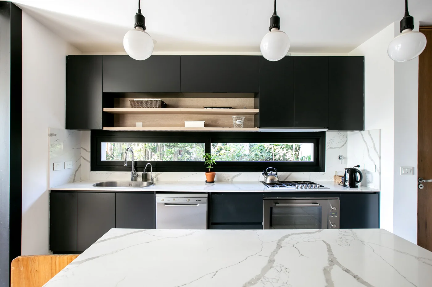 Cocina moderna con gabinetes negros y mesada de mármol blanco