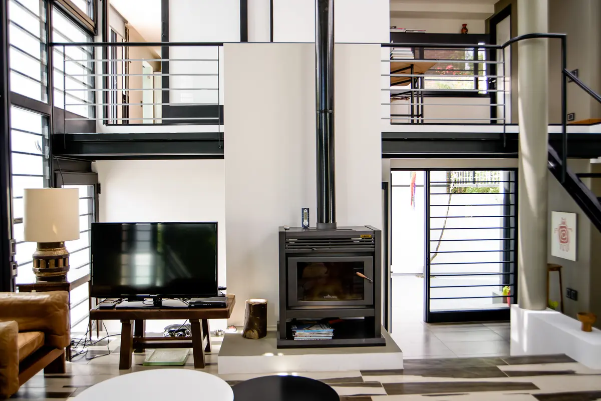 Sala moderna com pé-direito duplo, lareira e janelas amplas — projeto CASA GONNET, por LEONE LORAY ARQUITECTOS, em Gonnet
