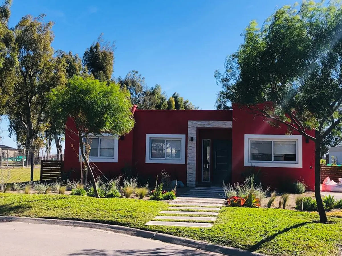 Casa moderna bordo con jardin y árboles bajo cielo despejado — proyecto Proyecto Santa Elena, por Celina Sammartino Paisajismo, en Pilar