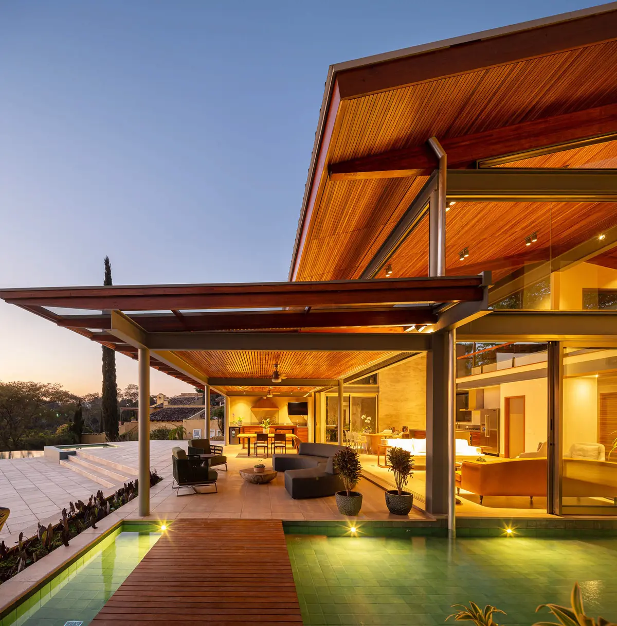 Casa moderna com piscina, pátio de madeira e sala de estar externa — projeto Casa JLB, por Manuel Sá