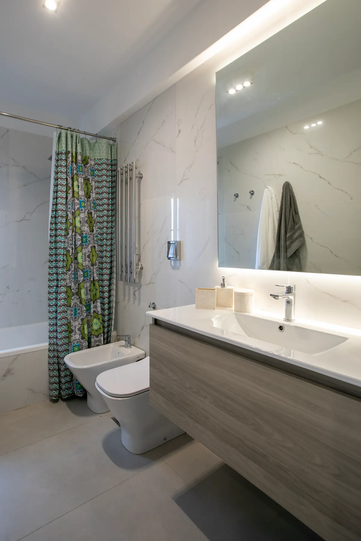Baño moderno con paredes de mármol, luz indirecta y vanitory de madera — proyecto Obra Araoz A, por Arq. Lourdes Yarade Saravia, en Buenos Aires