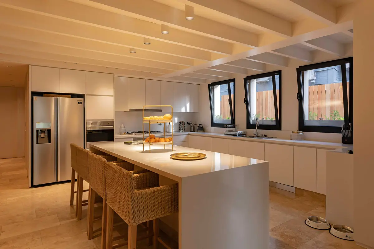 Cozinha moderna integrada com ilha grande e vigas expostas — projeto Las Marías, por Santiago Cordeyro Arquitectos, em San Isidro