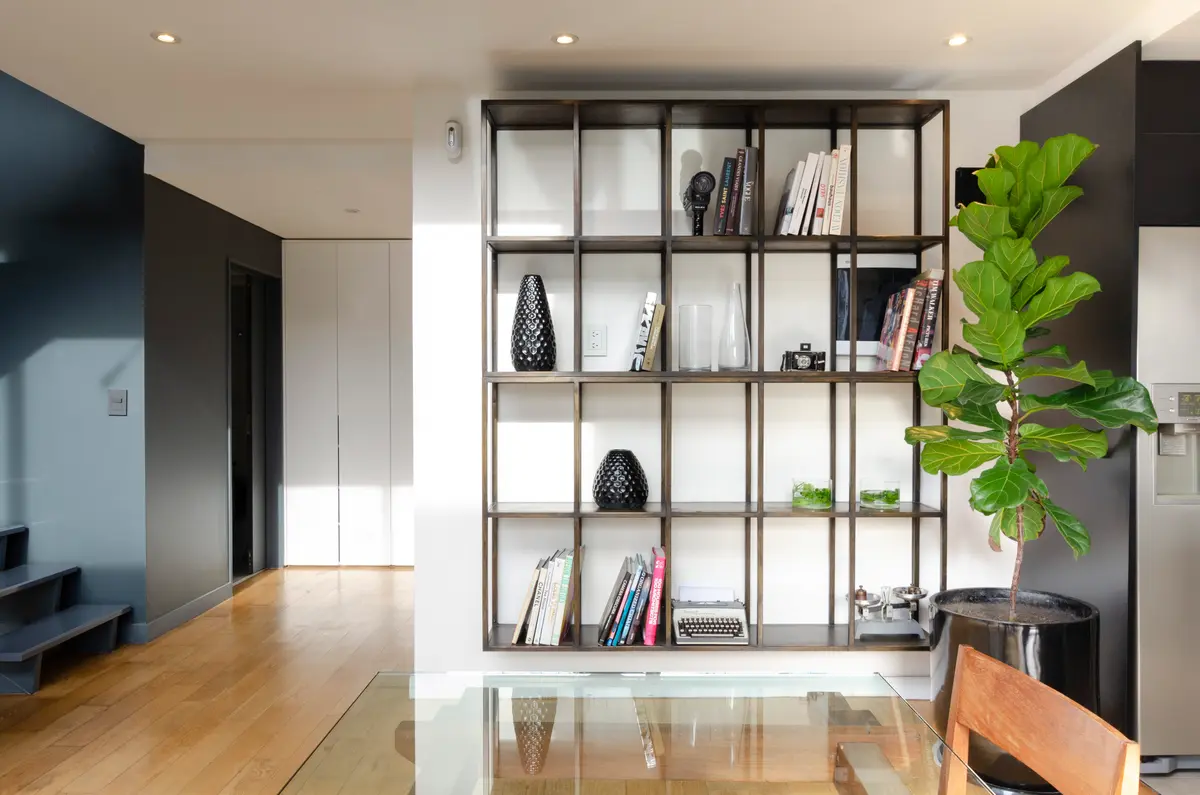 Estantería alta abierta en living moderno con planta interior — proyecto Guayra - Andrea Gonzales, por ABEJA CONCEPT, en Belgrano