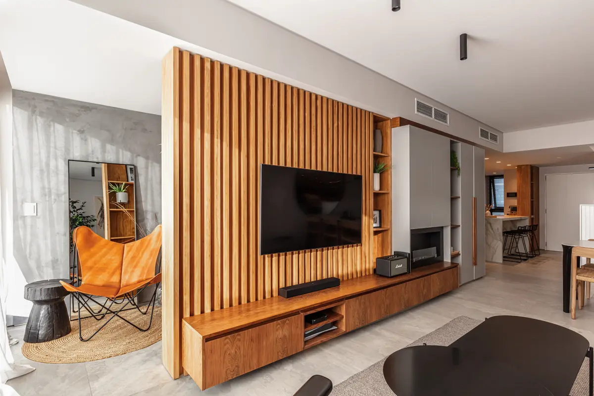 Sala de estar moderna com parede de ripas de madeira e poltrona laranja — projeto Depto Valle, por Ayelen Mayer Arquitectura, em Buenos Aires
