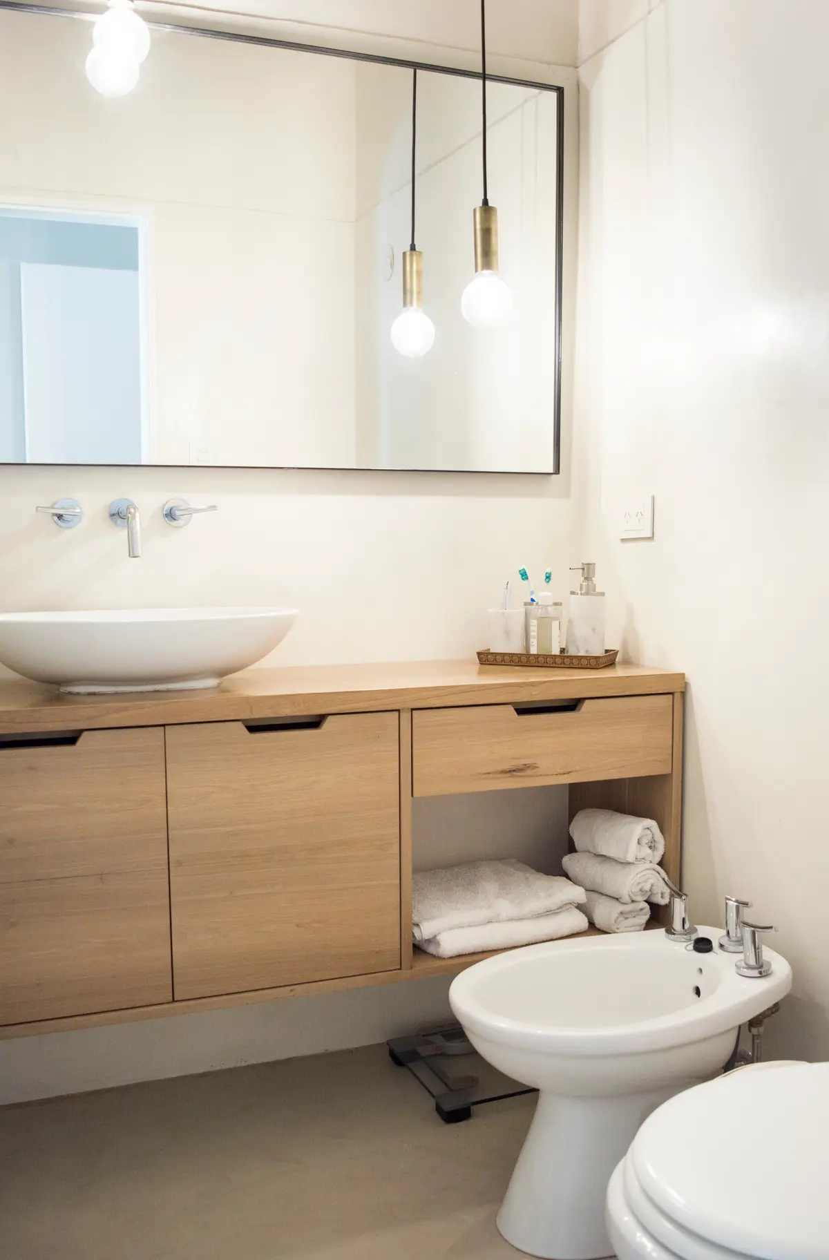 Baño moderno con vanitory de madera clara, bacha de apoyar y bidet — proyecto Pliar Green, por Equipe, en Pilar