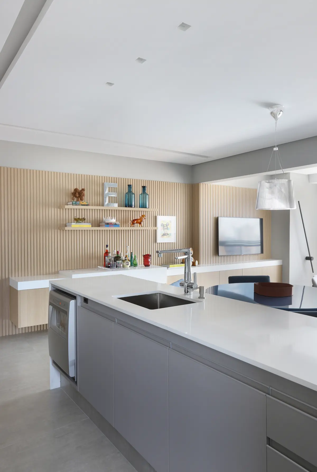 Cozinha moderna com ilha, parede de ripas de madeira e bancada em cascata — projeto Projeto Destaque Club&Casa, por Carlos Navero Arquitetura & Design