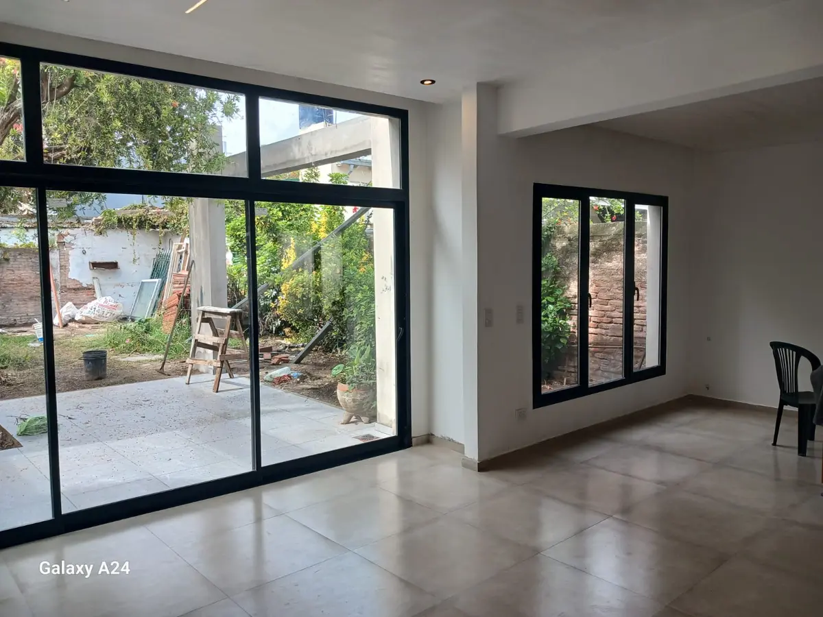 Sala de estar moderna conectada a patio exterior con grandes ventanales — proyecto Casa zABALA, por Sep Arquitectura , en La Plata