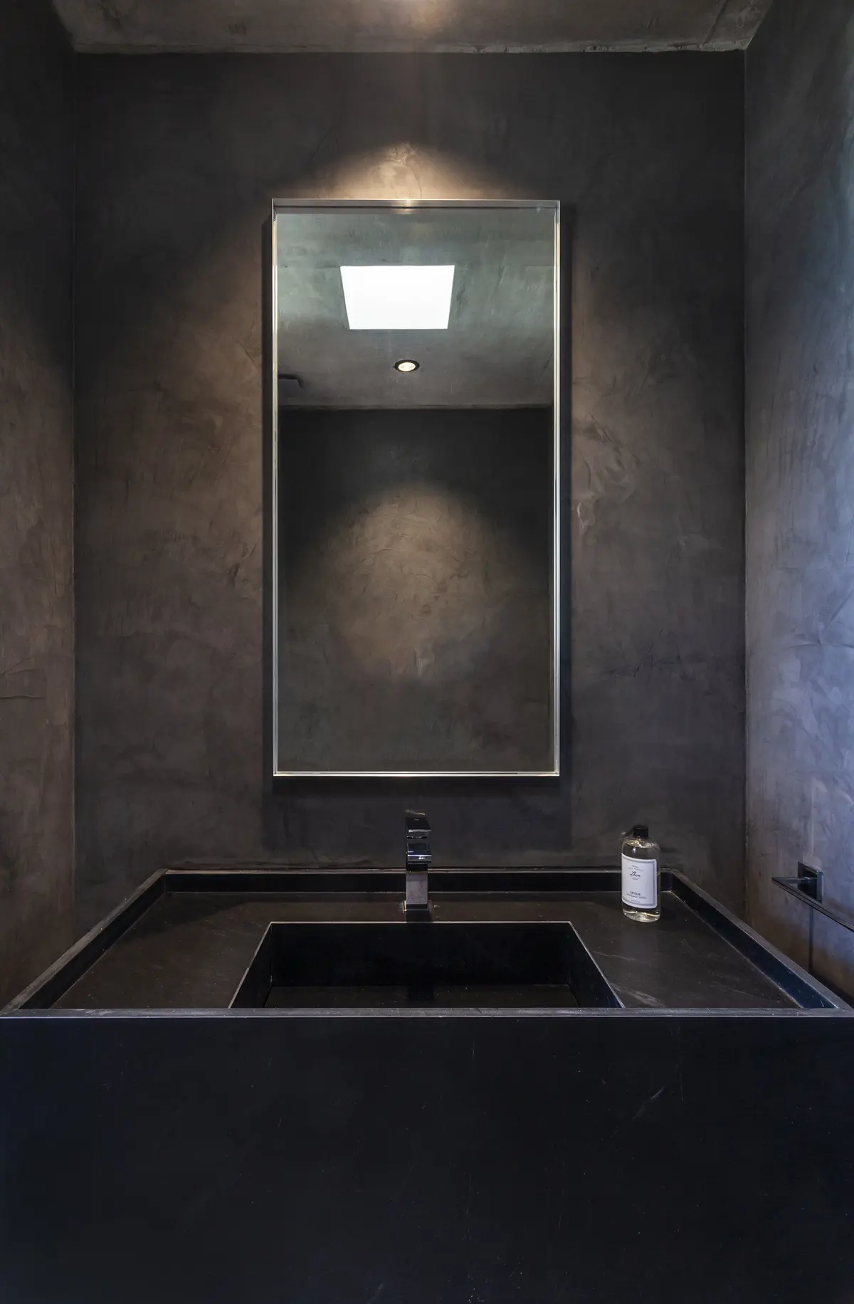 Baño moderno con paredes de microcemento y espejo rectangular — proyecto CASA FELIX, por GMARQ, en Pilar