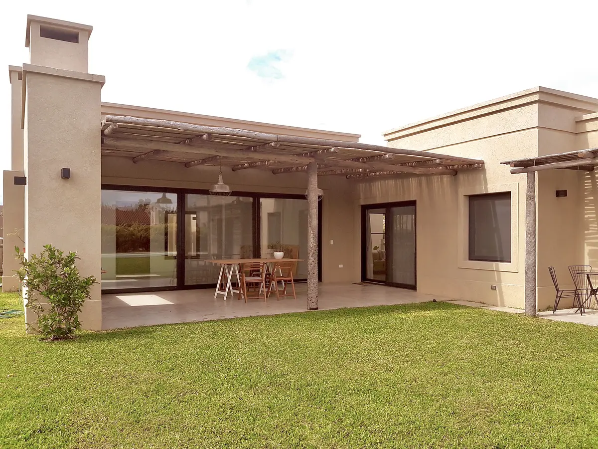Amplo jardim com pérgola de madeira e fachada moderna bege — projeto Santa Teresa 2, por Marconi Silva Arquitectos, em Benavidez