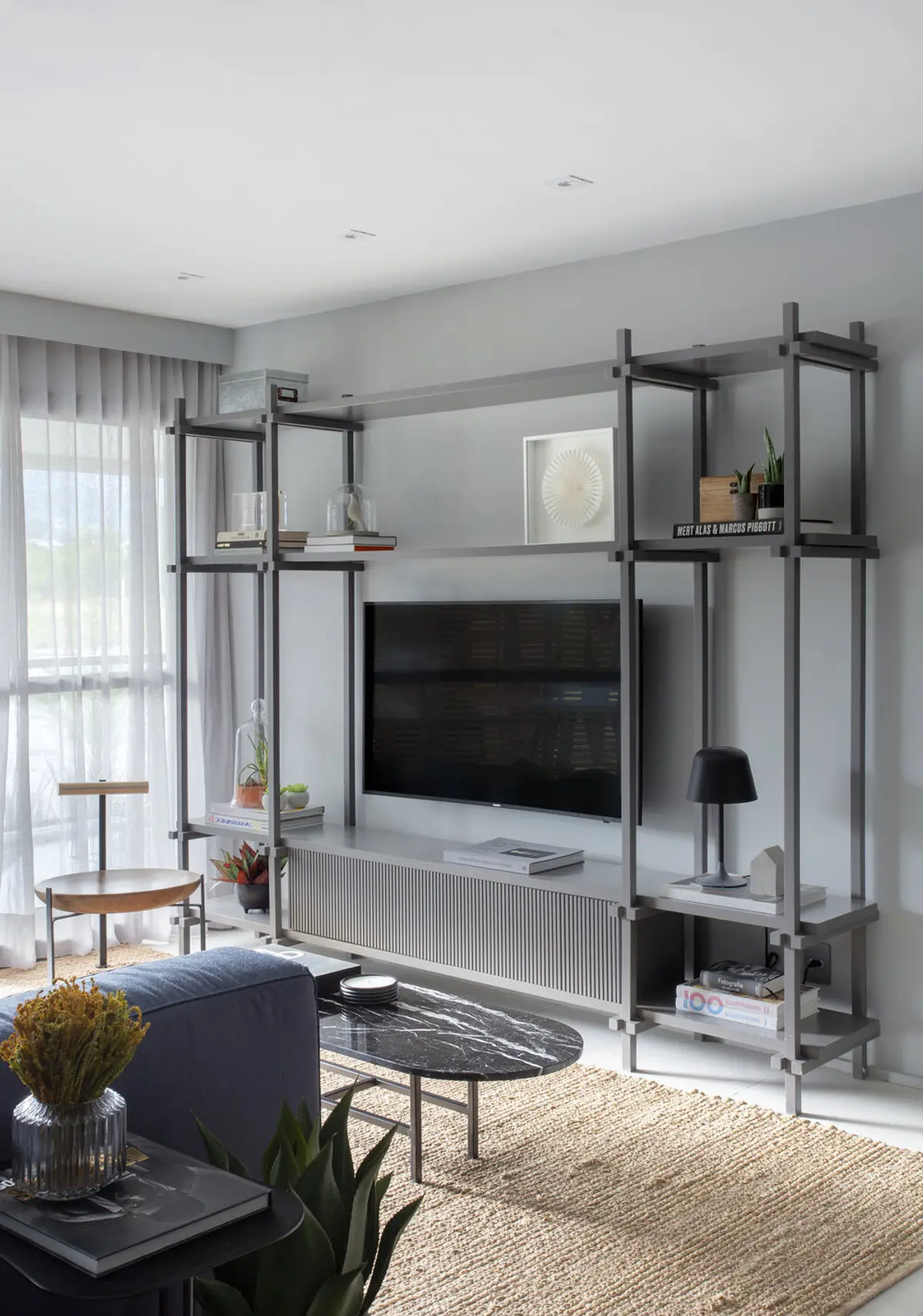 Living moderno con estantería negra, TV integrada y luz natural — proyecto Decorado Latitud, por Studio Ro-ca
