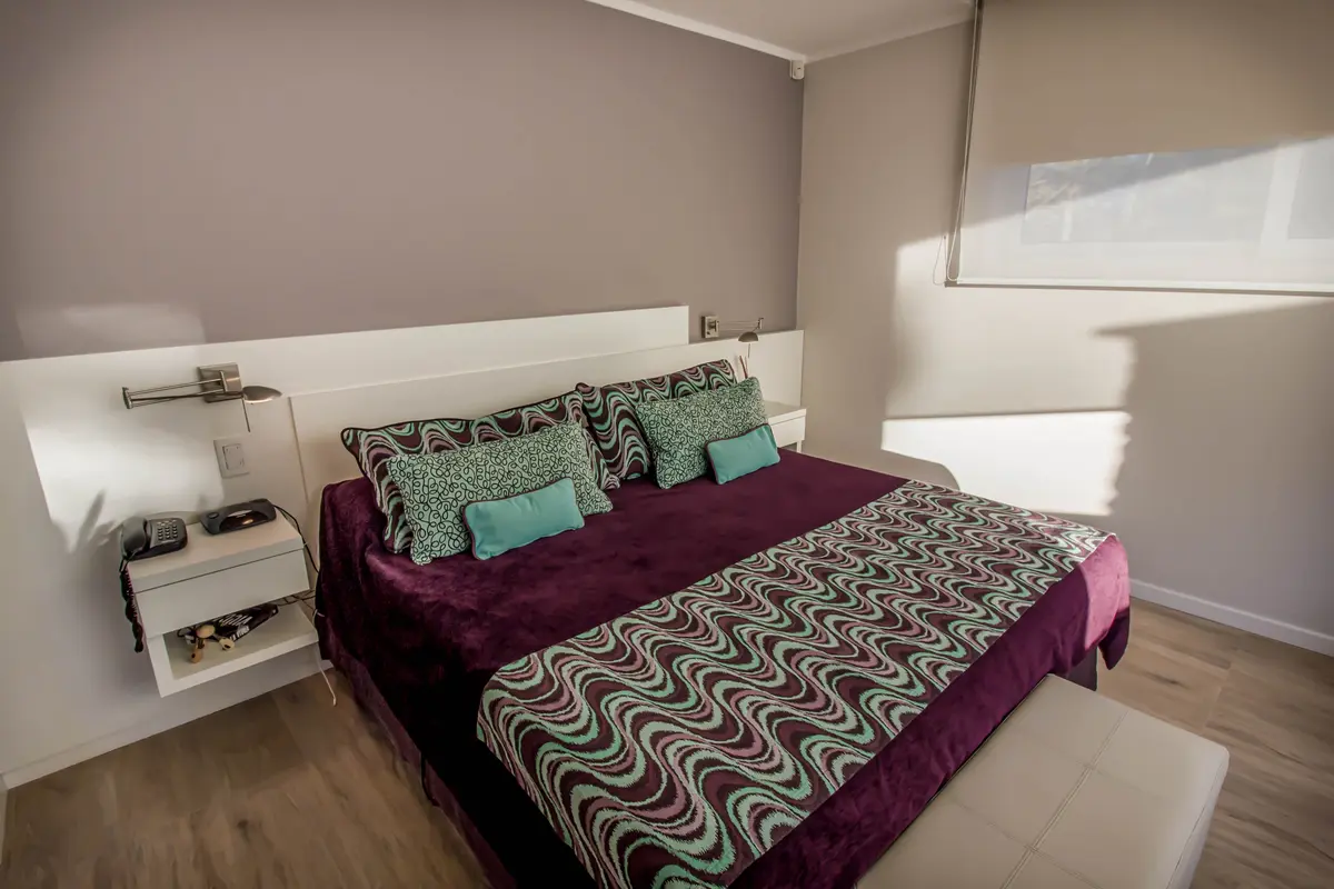 Dormitorio moderno con cama grande y alfombra geométrica — proyecto Vivienda Unifamiliar en Pinamar, por Estudio Schifano, en Pinamar