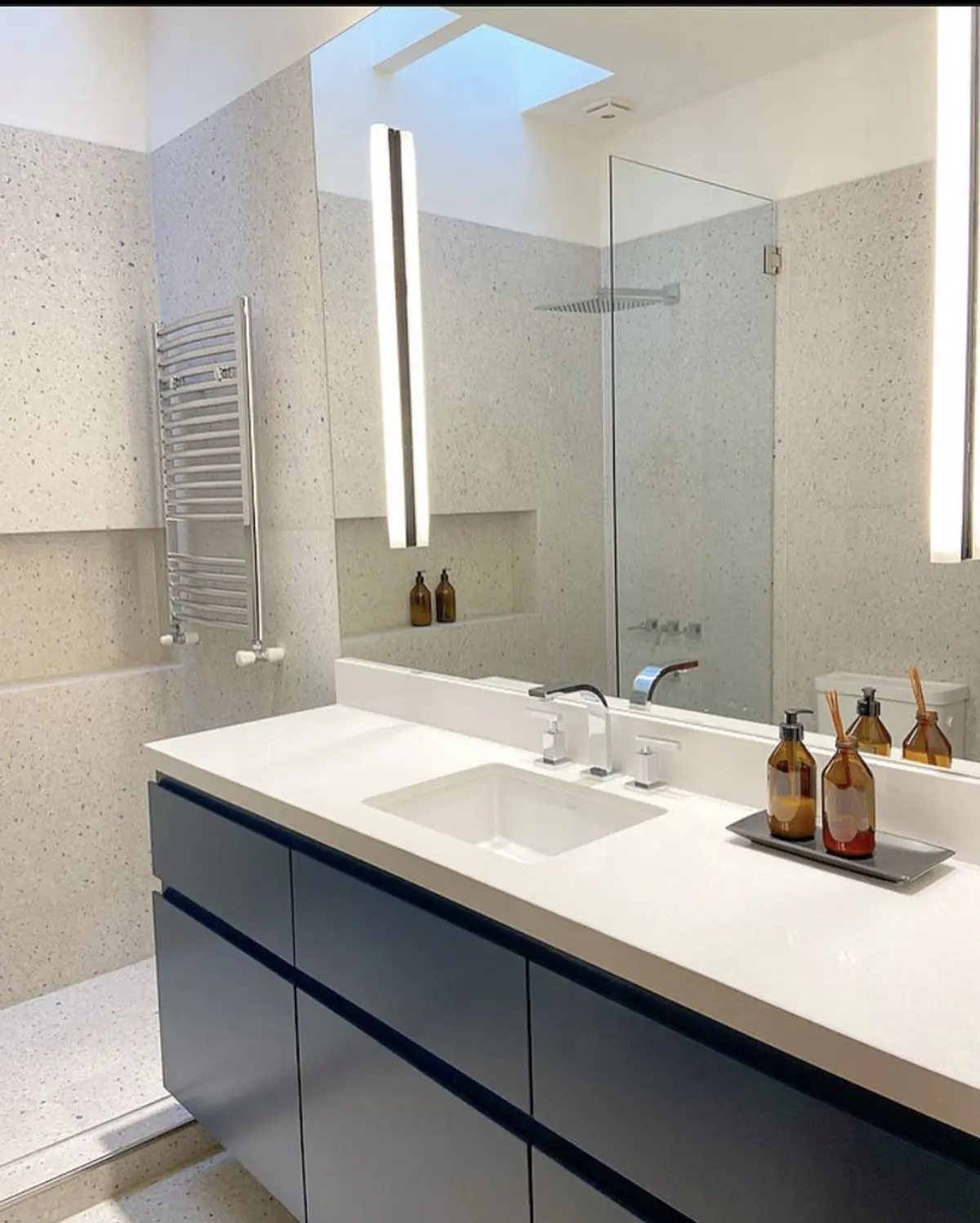 Banheiro moderno com bancada azul escura, bancada de pedra e box de vidro — projeto Baños Belgrano, por Cudini Estudio, em Belgrano
