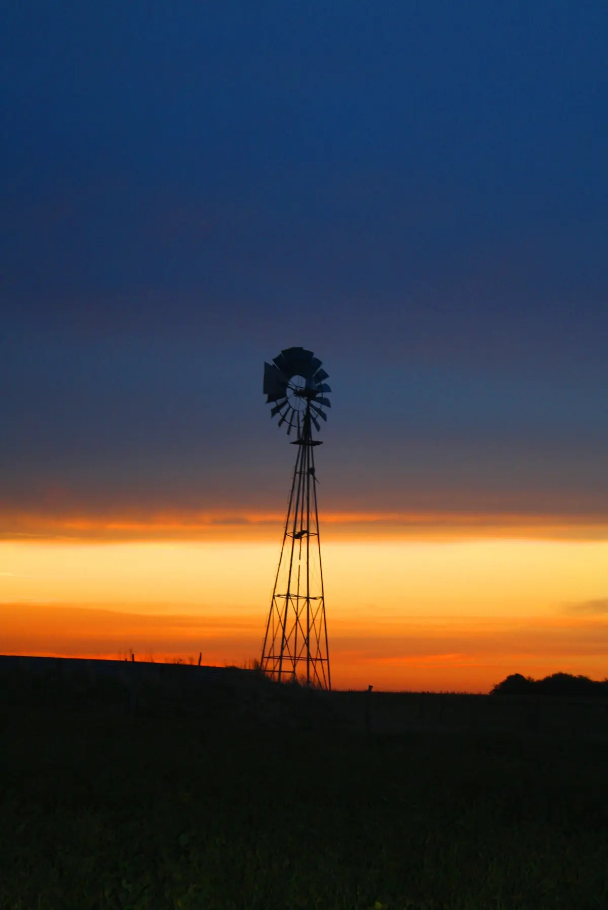 moinho de vento ao pôr do sol em campo rural — projeto Proyecto Santa Maria, por Estudio Arruabarrena, em Rincón de Milberg