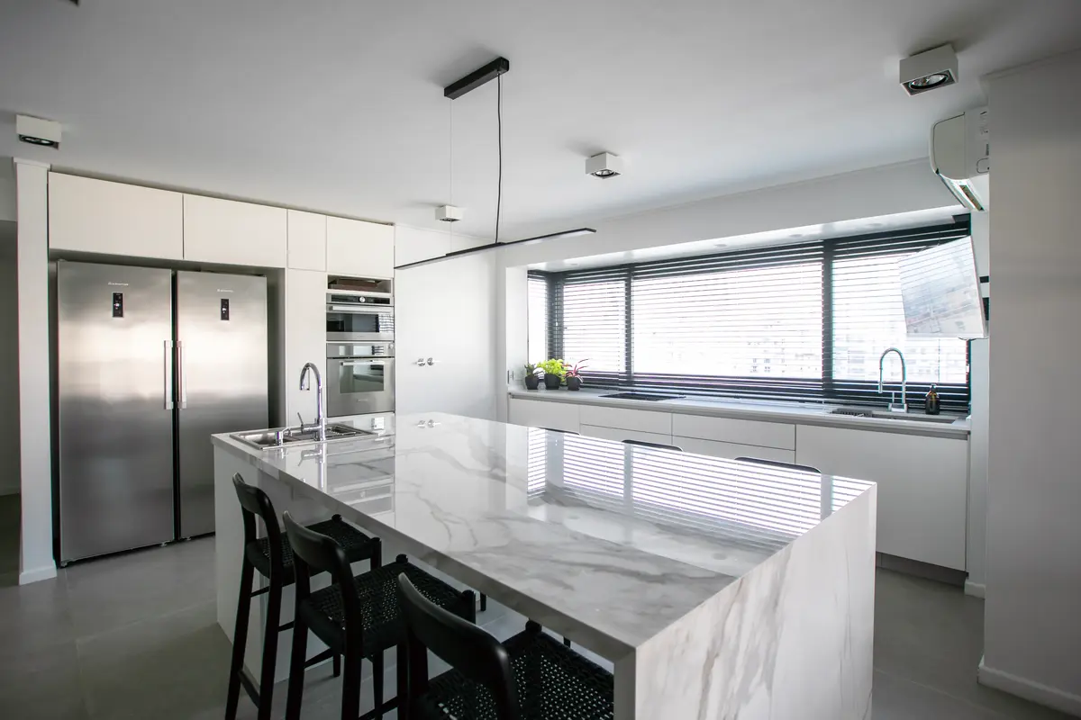 Cocina moderna con isla grande de mármol y ventanas hasta el techo — proyecto Obra Montevideo, por Arq. Lourdes Yarade Saravia, en Buenos Aires