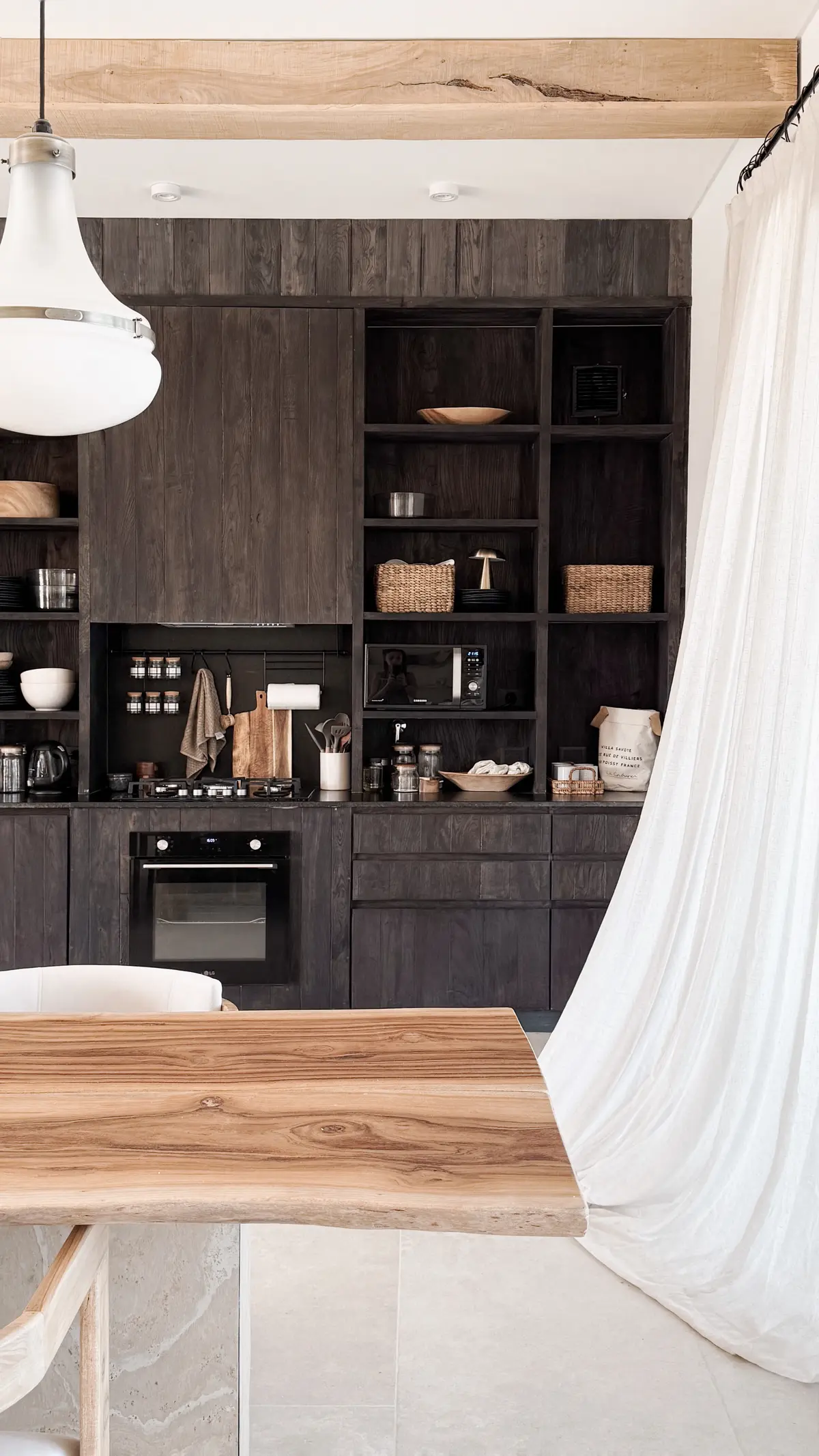 Cozinha rústica com mesa de madeira natural e vigas expostas — projeto El Refugio, por Grupo Pauta Arquitectura, em Pinamar