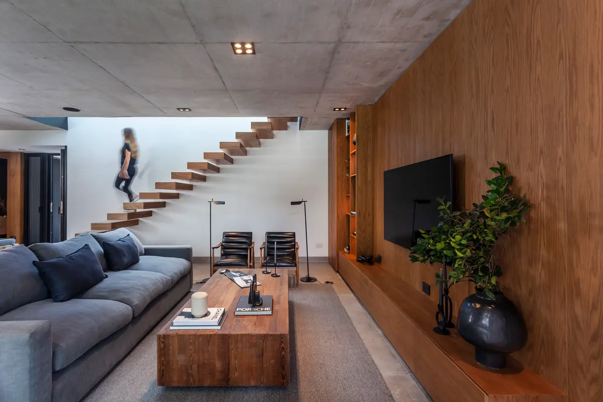 living moderno con escalera flotante y pared de madera — proyecto CASA AH, por GMARQ, en Garin