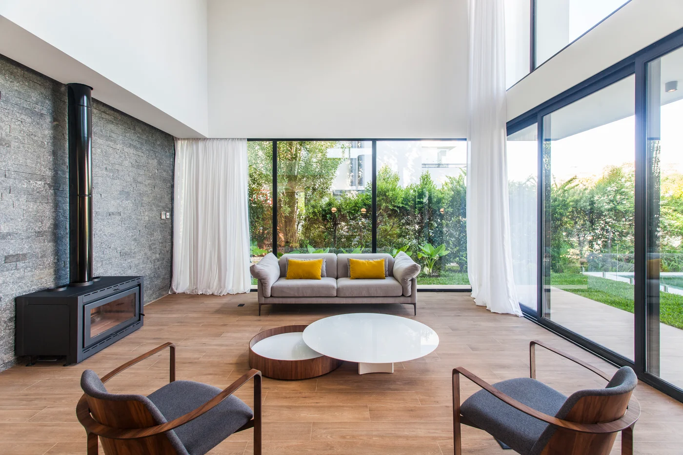 Living moderno con chimenea negra y grandes ventanales.