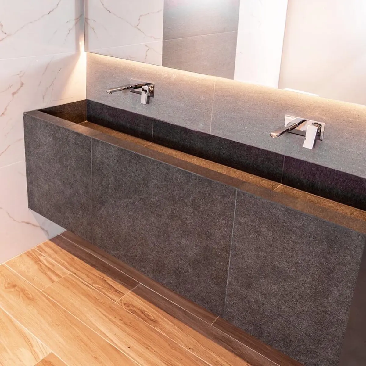 Baño moderno con doble bacha integrada de piedra oscura y luces cálidas — proyecto Showroom para Vite Porcellanatos (Buenos Aires) German Salas arquitecto, por German Salas arquite