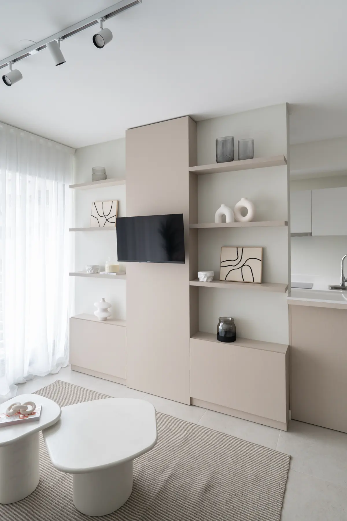 Sala de estar minimalista com estante modular bege e mesas de centro orgânicas — projeto EVOQUE, por MB Díseño Interior, em Buenos Aires