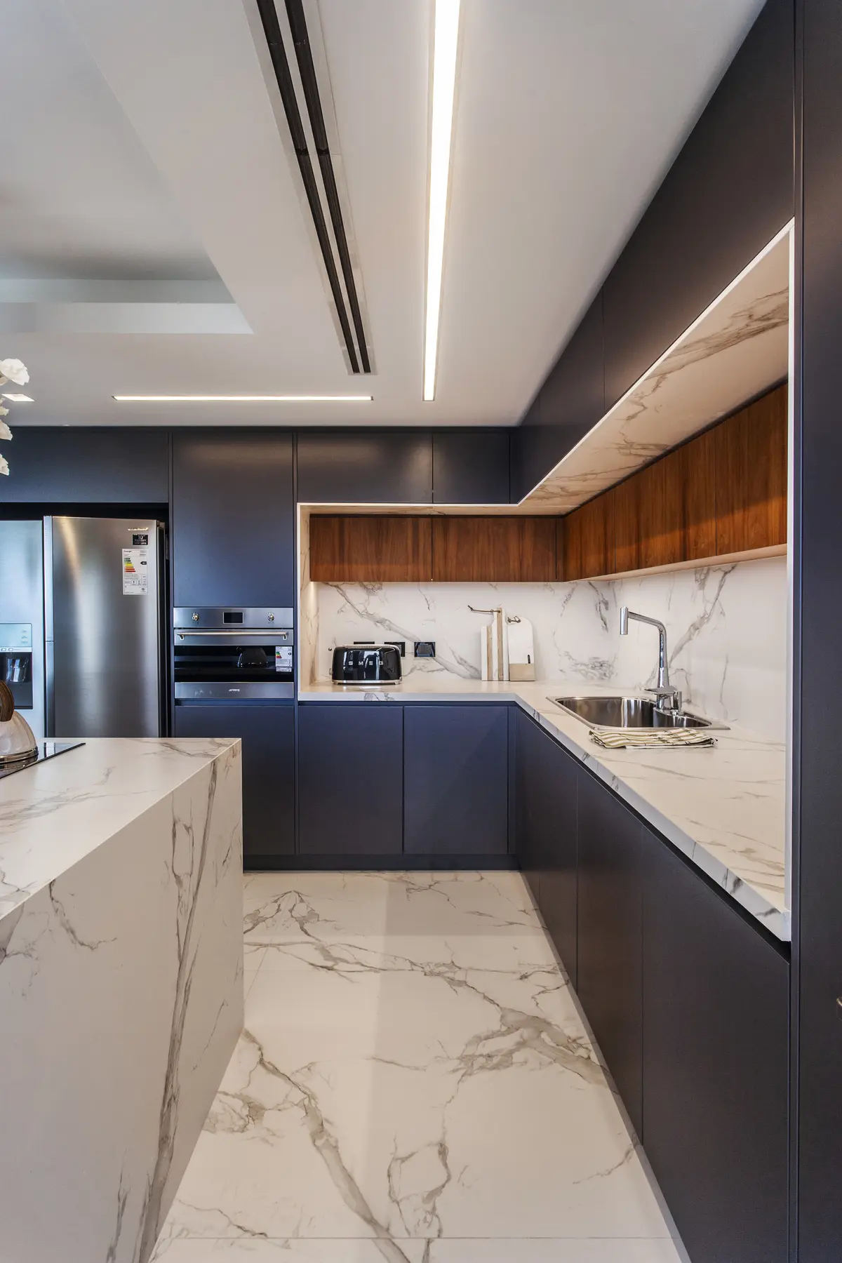 Cocina moderna con isla de mármol, muebles grises y luz integrada — proyecto Pacífico BRT, por Vanguarda Arquitectos, en CABA