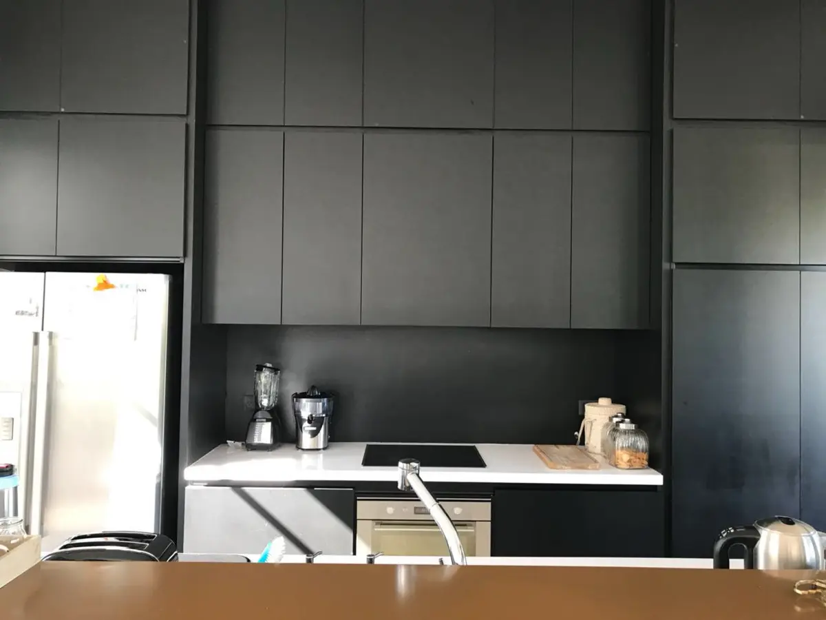 Cocina moderna con muebles oscuros integrados y electrodomésticos empotrados — proyecto Casa Las Liebres, por Mazzinghi Sanchez, en Garin