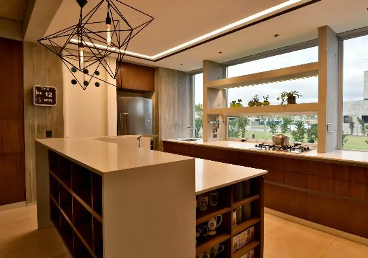 Cocina moderna con isla, ventanales y mobiliario de madera integrado — proyecto CASA GOLF III, por Alejandra Pan Arquitectura, en Nordelta