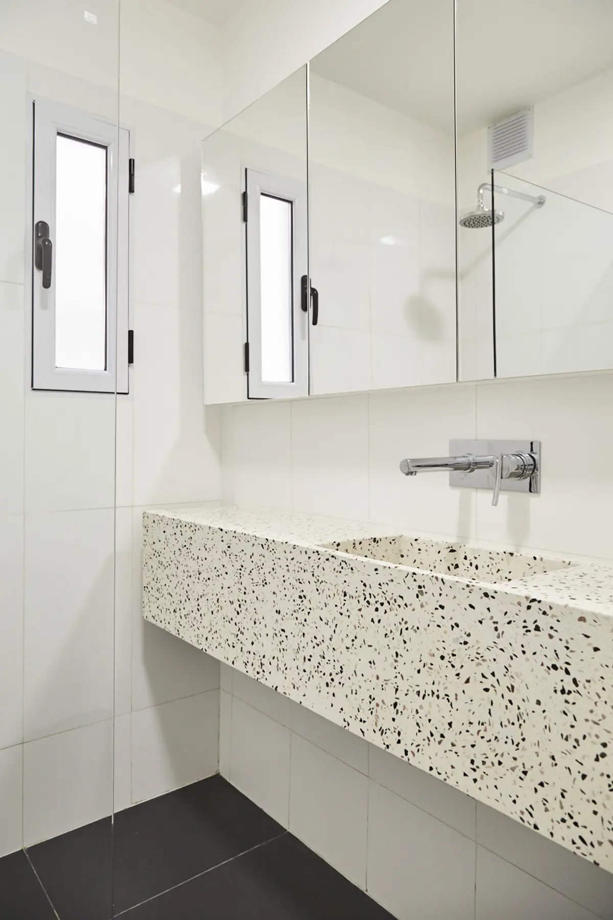 Baño moderno con lavabo de terrazzo y ventana alta — proyecto BERUTI 3, por Estudio Trama, en Palermo