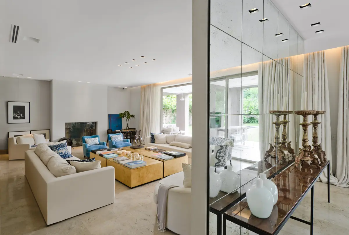 Sala de estar e jantar moderna com luz natural, paredes espelhadas e sofás amplos — projeto Casa H, por Estudio Dado, em Belgrano