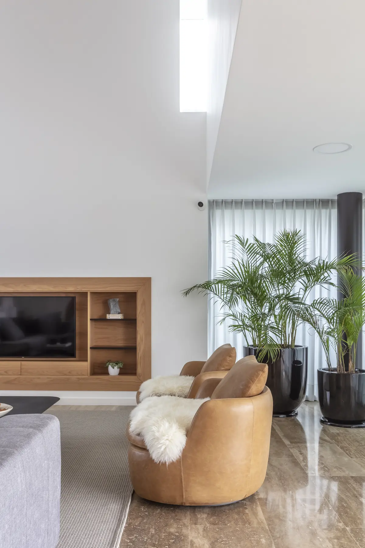Sala de estar moderna com pé-direito duplo, claraboia e poltronas de couro — projeto Nordelta, por Judith Babour, em Nordelta