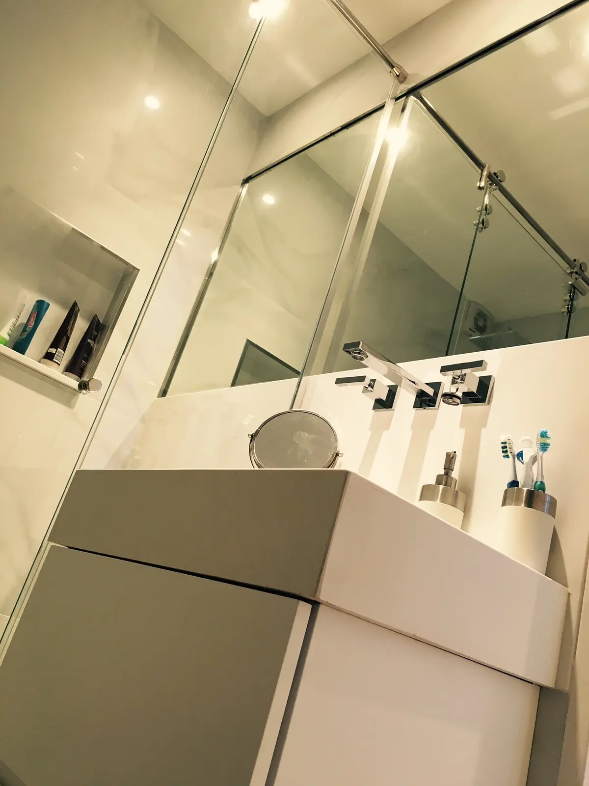 Moderno baño con vanitory flotante gris y mampara de vidrio templado — proyecto Ortega y Gasset, por Mgc.arq, en CABA