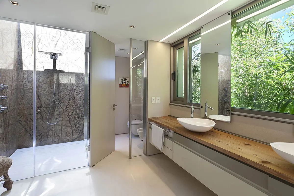 Baño moderno con ventana panorámica y vanitory de madera — proyecto Acasusso, por Remy Arquitectos, en Acassuso